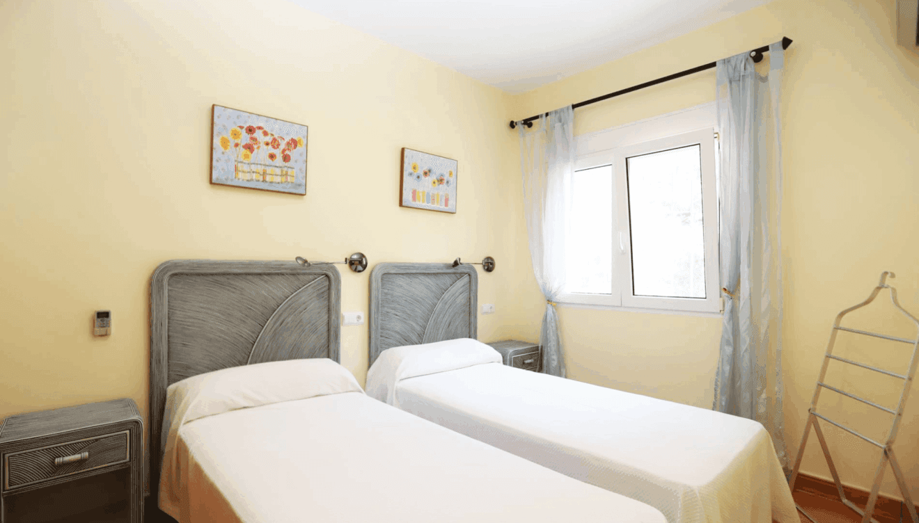 Segundo dormitorio luminoso con amplias ventanas y mobiliario moderno