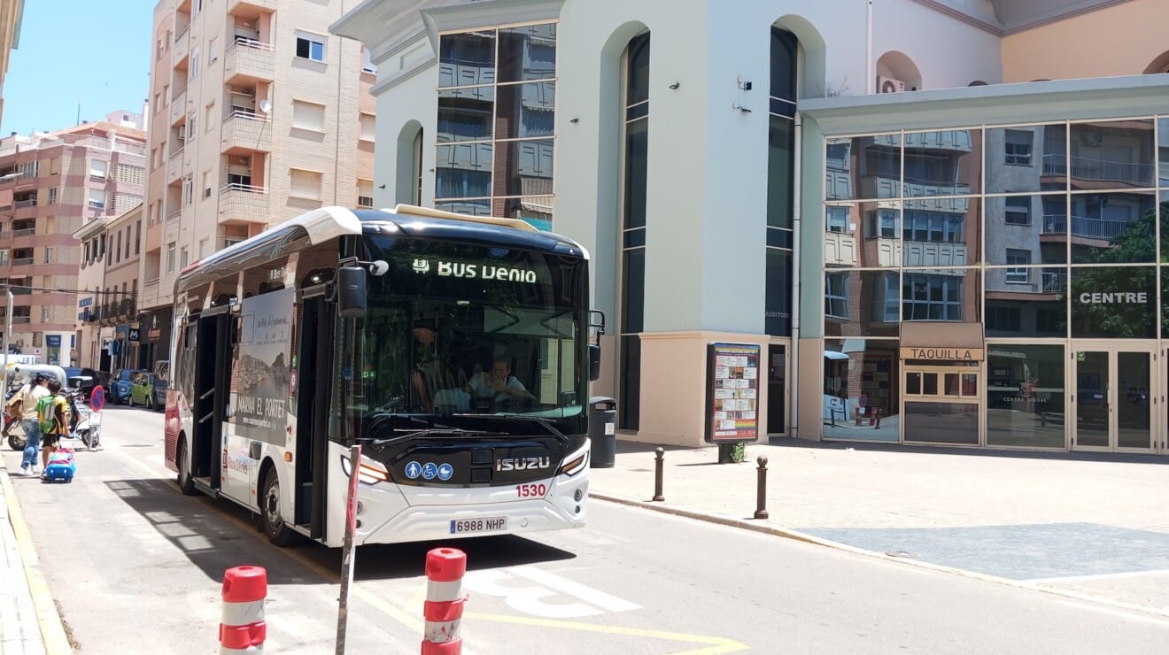 Autobús de la flota Bus Dénia estacionado en la parada frente al edificio del Centre Social