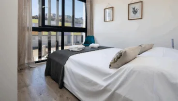 Dormitorio muy iluminado por sus grandes ventanales