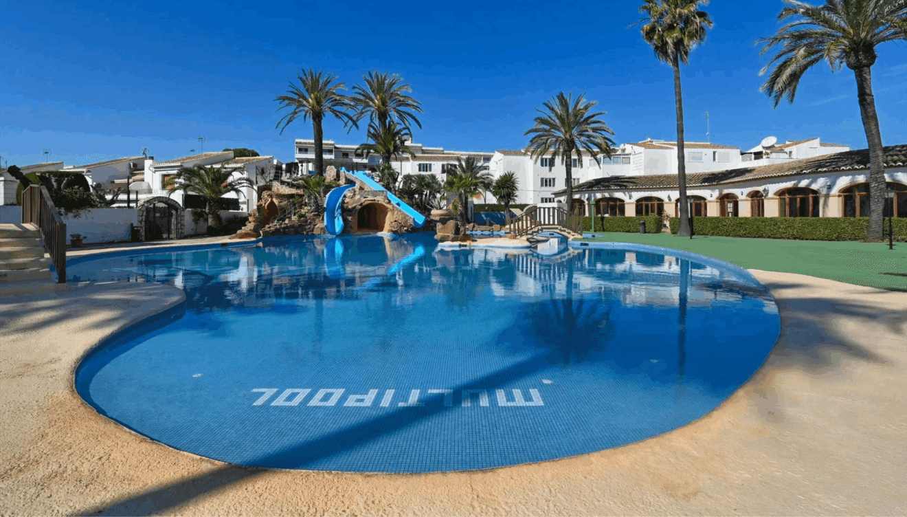 Gran piscina comunitaria con toboganes y espectaculares jardines