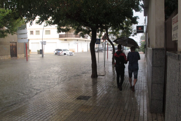 Afbeelding: Jongeren onder de paraplu naast een ondergelopen laan in Dénia tijdens een periode van hevige regen