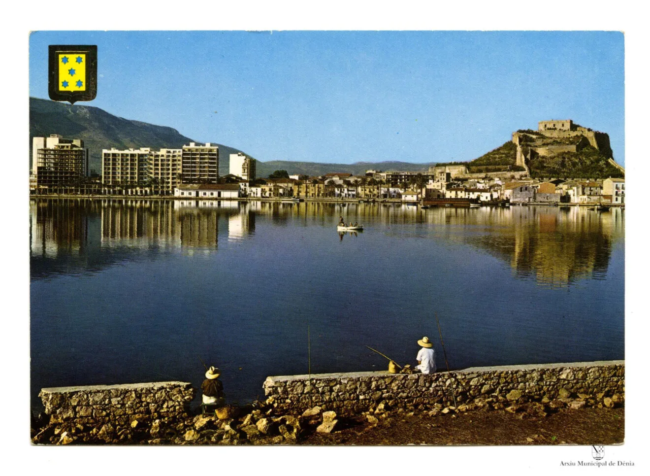 Gente pescando en el puerto de Dénia con la fachada portuaria en plena construcción | Arxiu Municipal