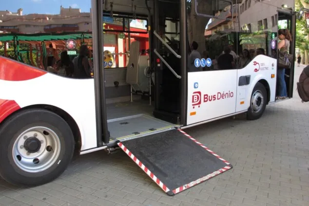Imagen: Autobús eléctrico de Bus Dénia con la rampa de accesibilidad de metal completamente extendida desde la puerta central hasta el pavimento de la calle