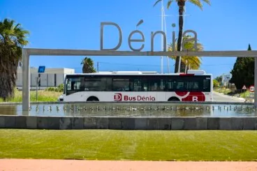 Nuevo autobús urbano híbrido de la flota BusDénia circulando junto al icónico monumento de entrada a la ciudad