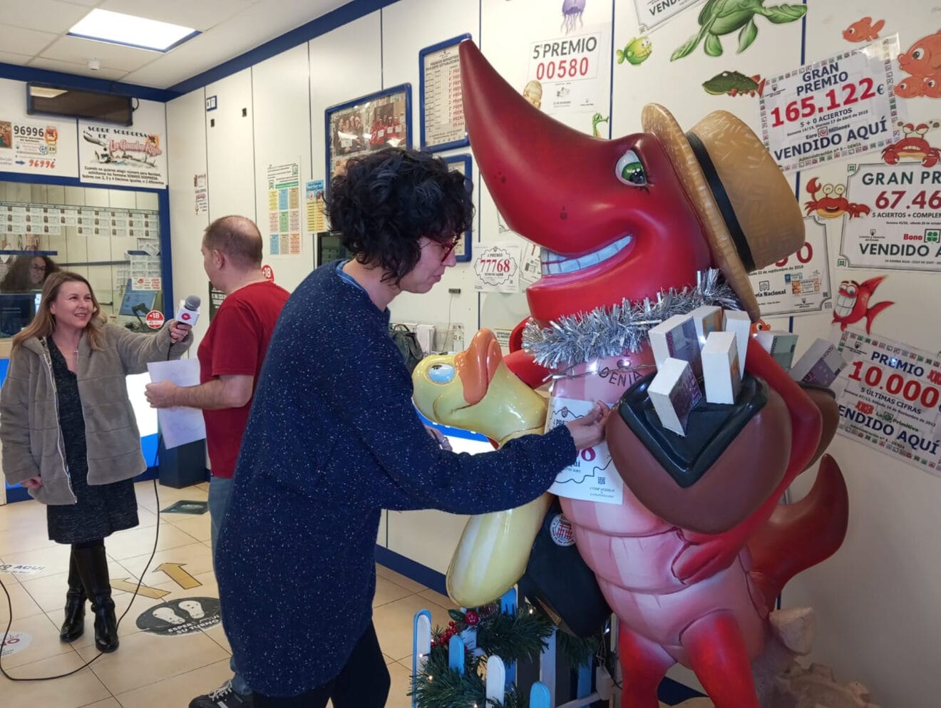 Trabajadores de la administración poniendo el número premiado en la gamba roja de Dénia