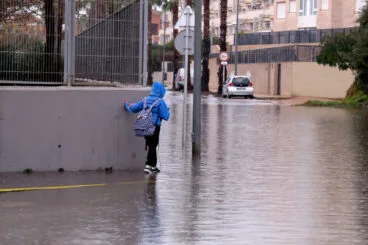 estudiante intentando llegar al instituto con la calle anegada por la lluvia