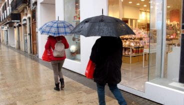 gente paseando con paraguas bajo la lluvia en el centro de denia