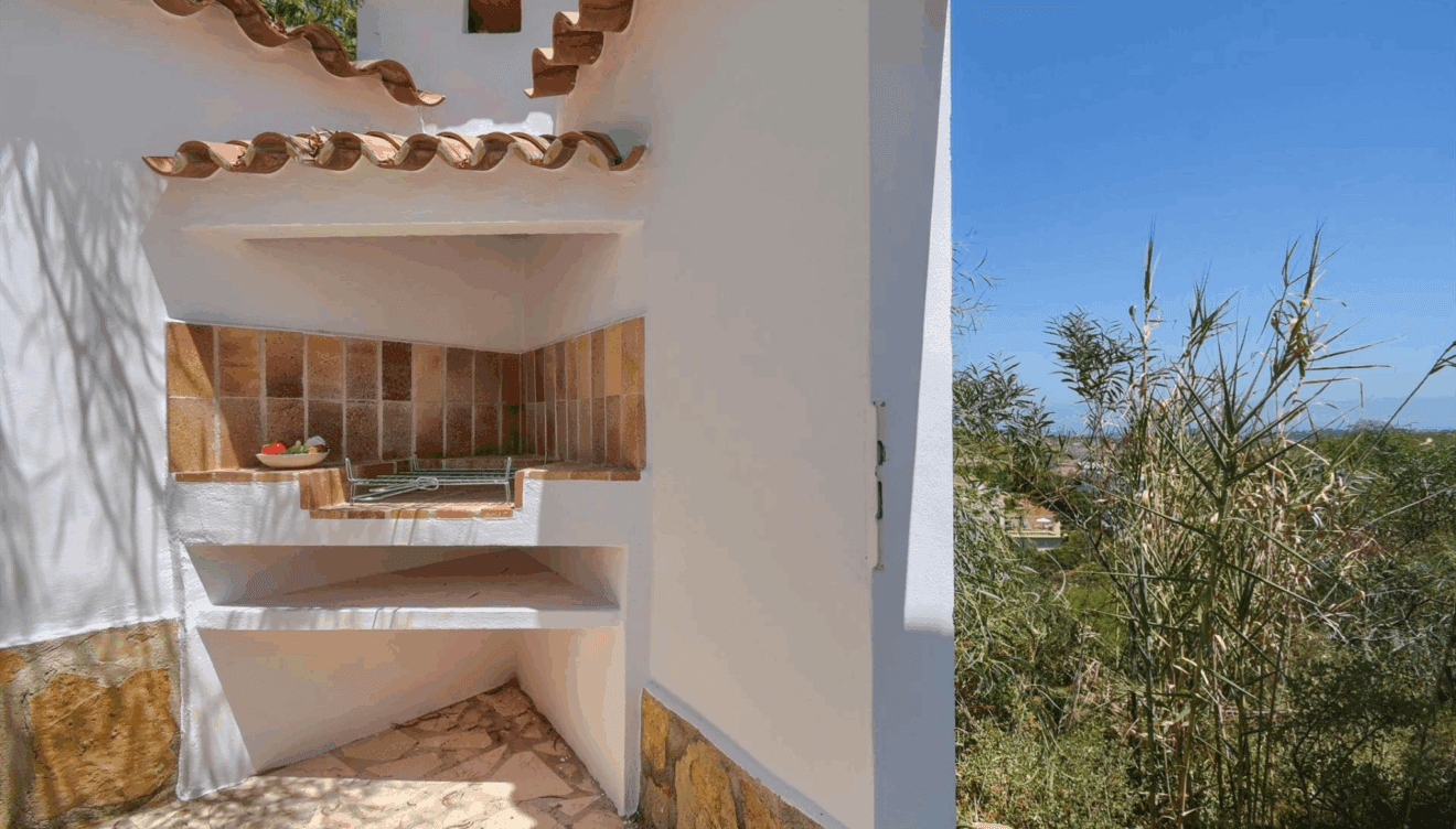 Zona de barbacoa al aire libre con entorno mediterráneo y vistas abiertas