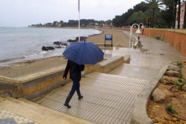 persona paseando bajo la lluvia en el paseo de la marineta cassiana de denia archivo