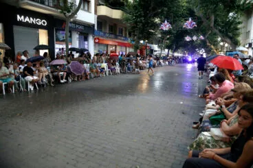 publico aguardando bajo la lluvia al desfile de carrozas y comparsas 2025 de denia
