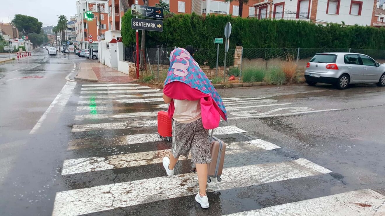 Peatón con una maleta resguardándose de la tormenta veraniega de Dénia