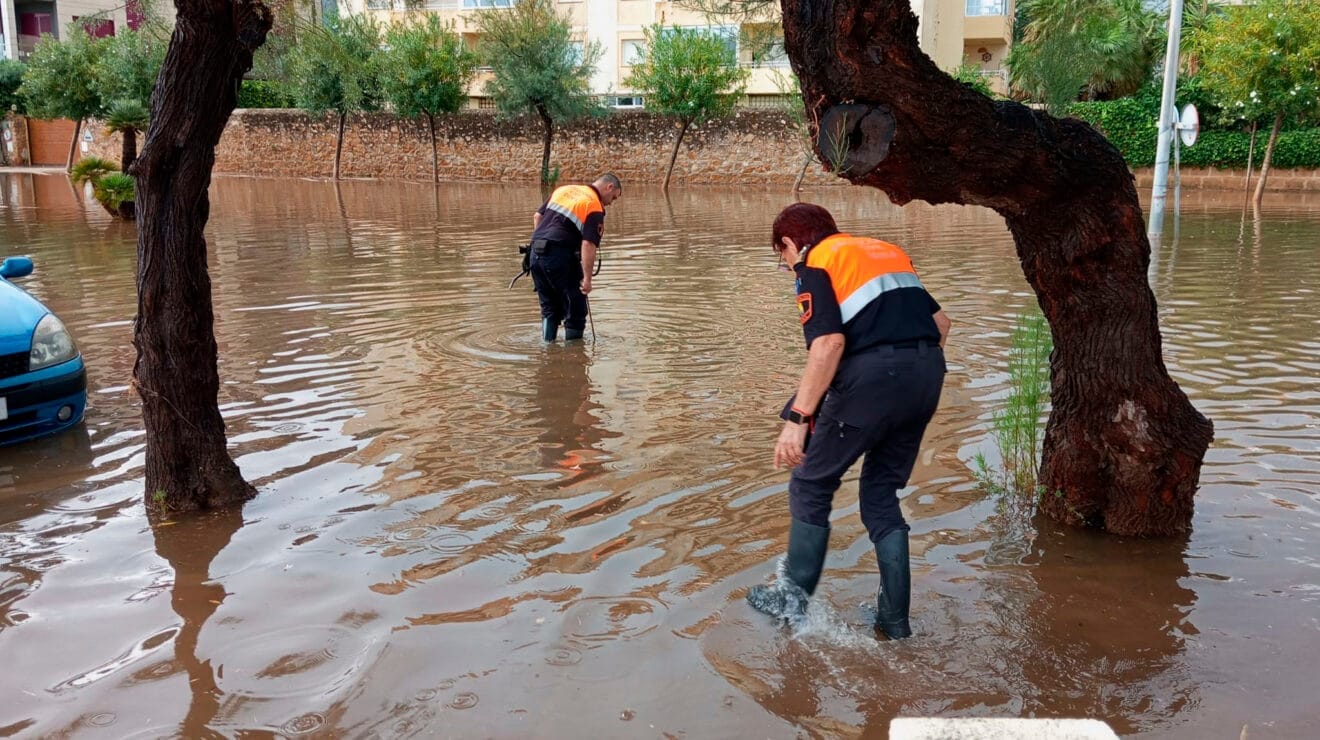 Voluntarios de Protección Civil en una vía anegada de Dénia