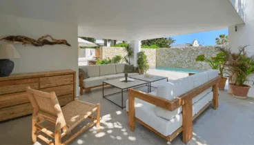 Comedor exterior cubierto con vistas al jardín y piscina