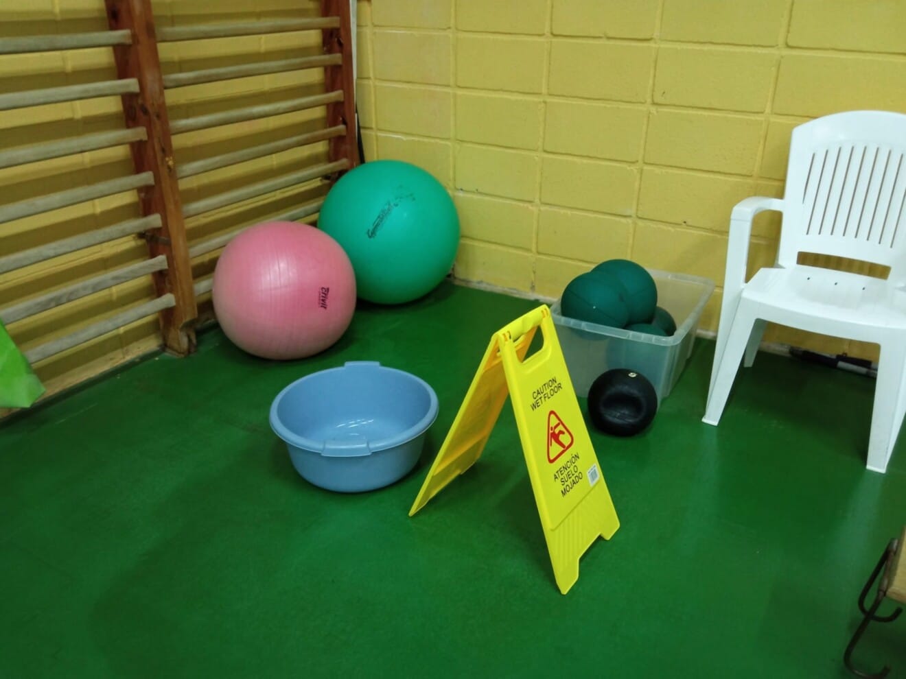 Cubos y señalización de suelo mojado colocados en una sala para contener filtraciones de agua durante la actividad