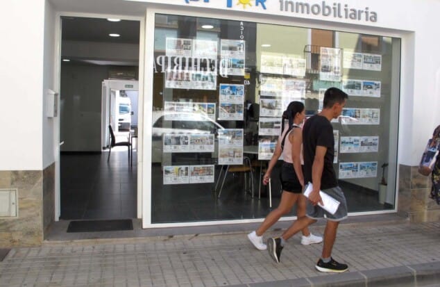 Imagen: Jóvenes pasando de largo ante el escaparate de una inmobiliaria de Dénia