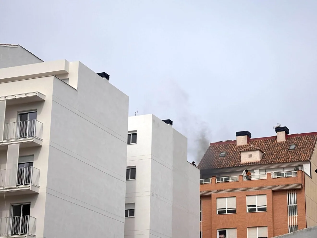 densa columna de humo negro saliendo de la ultima planta del edificio afectado en el carrer benissa en el barrio saladar de denia