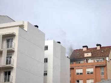 densa columna de humo negro saliendo de la ultima planta del edificio afectado en el carrer benissa en el barrio saladar de denia