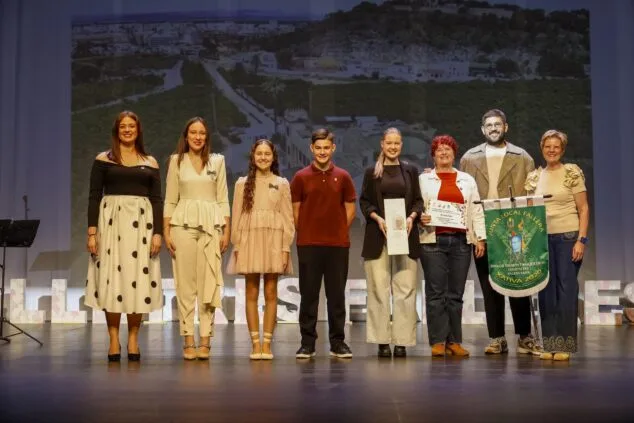 Representantes de la Falla Saladar reciben el premio al mejor diseño de llibret en un escenario.