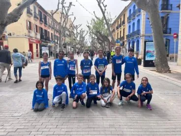 Grupo de jóvenes atletas del Club de Atletismo Baleària Diànium posando juntos en una calle de Dénia.