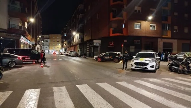 Streifenwagen und lokale sowie nationale Polizeibeamte auf einer Straße in Dénia bei Nacht.