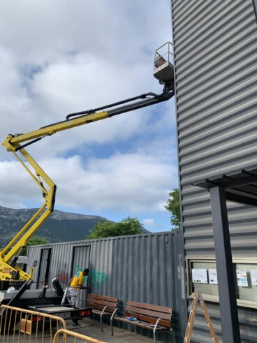 Un operario realiza tareas de repintado en la parte superior de la estructura vertical de la estación de autobuses de Dénia