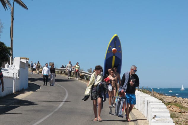 Imagen: Visitantes cargados con sillas y tablas de paddle surf recorren los accesos al litoral de Dénia ante la masiva llegada de turistas
