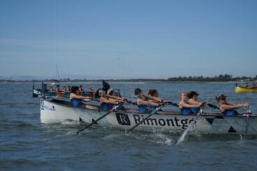 Equipo femenino de remo compitiendo en una embarcación de Llaüt Mediterráneo en el mar.
