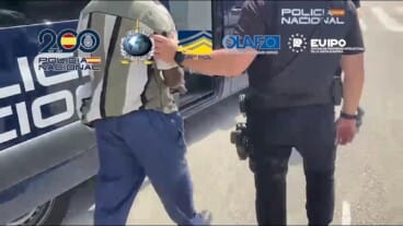 Agente de la Policía Nacional escoltando a una persona detenida, con las manos esposadas, durante una intervención