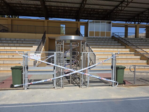 Imagen: Tornos de acceso a la grada de la pista de atletismo de Dénia bloqueados con cinta de balizamiento de la Policía Local.