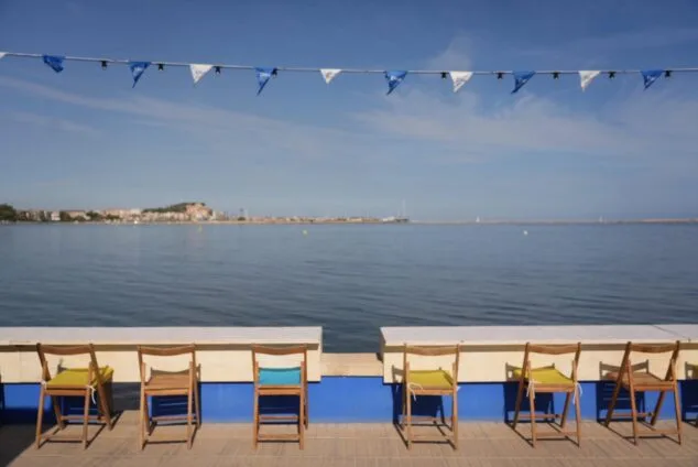 Imagen: Paseo marítimo de Dénia con sillas y banderas del D*na Festival frente al mar.