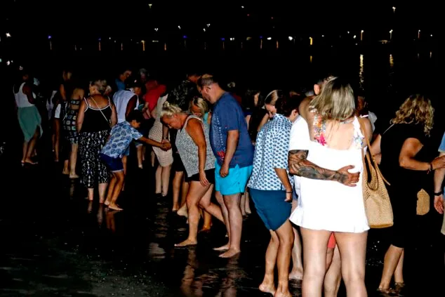 Personas celebrando la Noche de San Juan en la playa de Dénia por la noche.