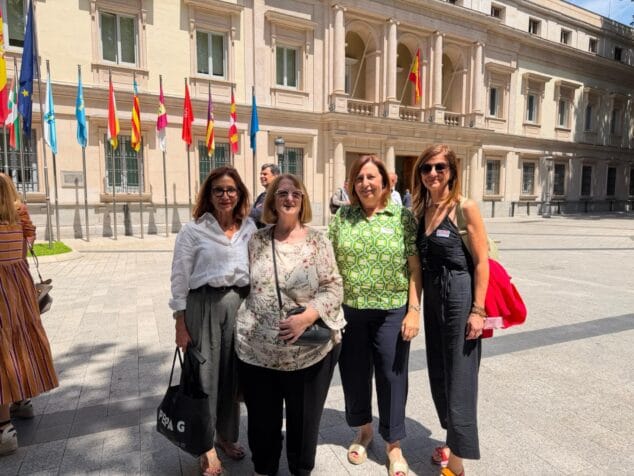 Imagen: Pepa Font junto a un grupo de mujeres frente a un edificio oficial con banderas en Madrid.