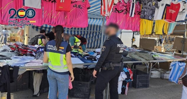 Cae una red de falsificaciones en Dénia: 12 detenidos y miles de artículos incautados 1 Imagen: Agentes de la Policía Nacional y Policía Local de Denia inspeccionando ropa y camisetas de fútbol en un puesto de mercadillo.