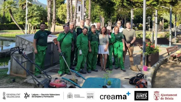 Foto de grupo del alumnado del Taller de Empleo de Jardinería de Creama junto a la concejala María José García Roselló y el técnico Carlos Costa en un parque de Dénia, con herramientas y logotipos institucionales al pie.