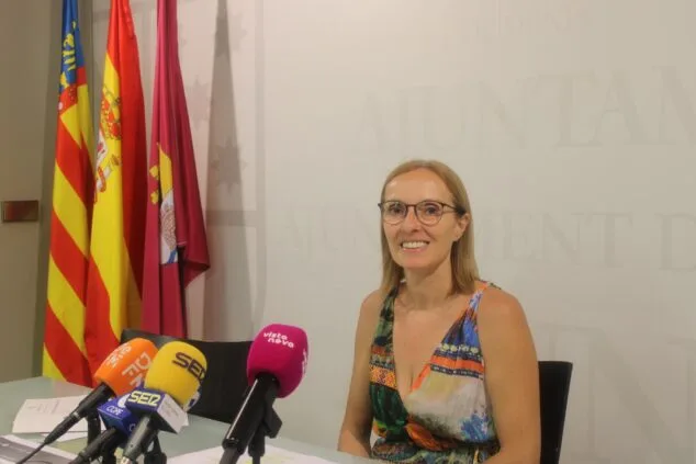 Imagen: Marta Gascó en rueda de prensa con micrófonos y banderas detrás.
