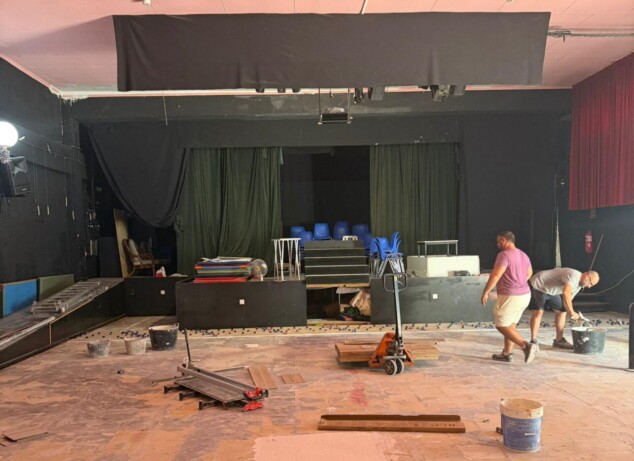 Imagen: Obras de renovación en el interior de la sala de la Escuela de Teatro Comarcal de Dénia, con el suelo levantado y operarios trabajando.