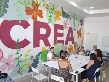 La Xarxa Jove y la MACMA impulsan el proyecto europeo ChildStory para la participación infantil en la Marina Alta 4 Varios profesionales sentados alrededor de una mesa blanca durante una reunión de trabajo del proyecto ChildStory.