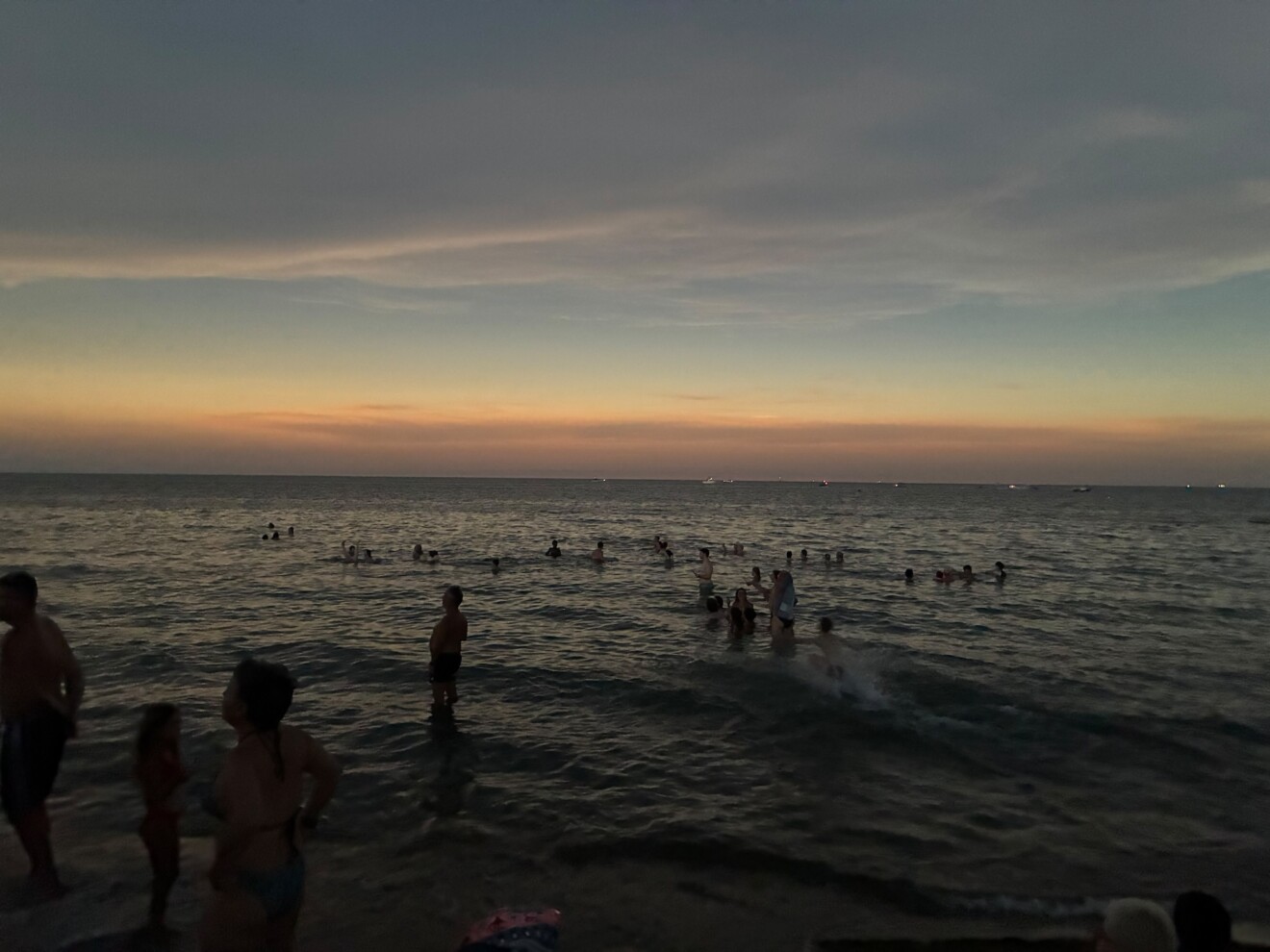 Bañistas en el agua durante los minutos de penumbra que cambiaron la luz de la costa dianense