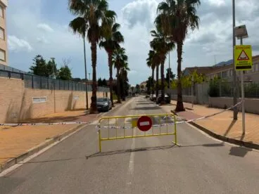 Una fuga de aguas residuales obliga a cerrar al tráfico el Camí del Llavador de Dénia 1 Una valla amarilla y cinta policial cierran el paso en una calle con palmeras, el Camí del Llavador, debido a obras.