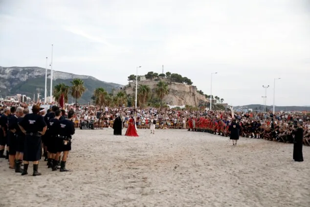 Dénia firma la tregua a orillas del mar: las tropas moras conquistan la escollera norte antes del gran choque 1 Imagen: Multitudinario aspecto de la playa de la escollera norte durante la representación, con el Castillo de Dénia de fondo