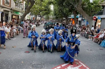 Escuadra de niños vestidos con trajes moros de color azul recorre la calle Marqués de Campo bajo los plataneros