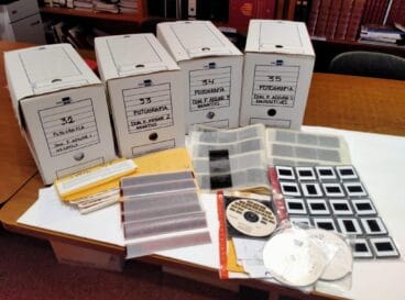 Más de 50.000 imágenes de la vida cotidiana de Dénia donadas por el fotógrafo Paco Adsuar 44 Cuatro cajas de archivo etiquetadas, tiras de negativos, diapositivas en fundas y CD sobre una mesa, parte de la donación de Paco Adsuar al Archivo de Dénia.