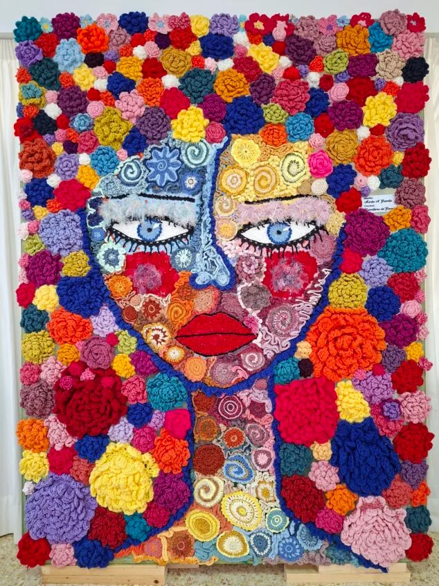 Tapiz de crochet colorido representando el rostro de una mujer.