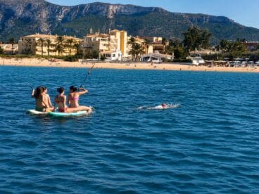 Complejo rescate en Dénia: un agente de la Policía Local salva a nado a seis jóvenes en paddle surf 2 Varias jóvenes sobre tablas de paddle surf en el mar alejadas de la playa de Dénia con montañas al fondo.