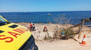 Fallece un hombre de 70 años tras sufrir un golpe en la cabeza en una playa de Dénia 3 Personal del SAMU en una zona costera rocosa donde yace una persona fallecida, con una ambulancia en primer plano.