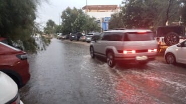 Vehículos circulando por una de las calles anegadas tras la tromba de agua