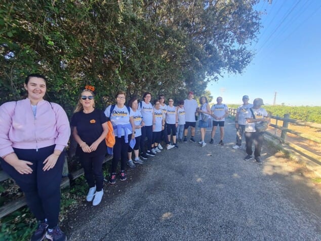 Ni gimnasio ni cuotas: el programa ‘Dénia Camina’ propone salidas en grupo dos días a la semana 1 Imagen: El grupo de 'Dénia Camina' posa junto a un campo antes de iniciar la marcha, algunos con camisetas oficiales