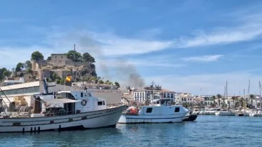 El humo se eleva sobre el perfil urbano de Dénia, visto desde el puerto