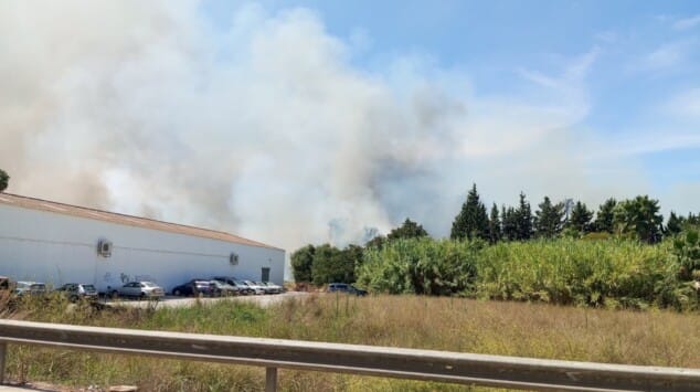 Incendio en Dénia: bomberos de tres parques y un helicóptero logran frenar el fuego que amenazaba a las casas 3 Imagen: El humo se eleva tras la nave industrial, alimentado por la maleza seca cercana