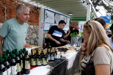 Un productor local atiende a una visitante en la parada de aceite de oliva artesanal